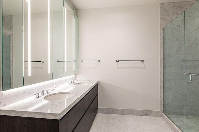 full bath featuring a sink, a shower stall, baseboards, and double vanity