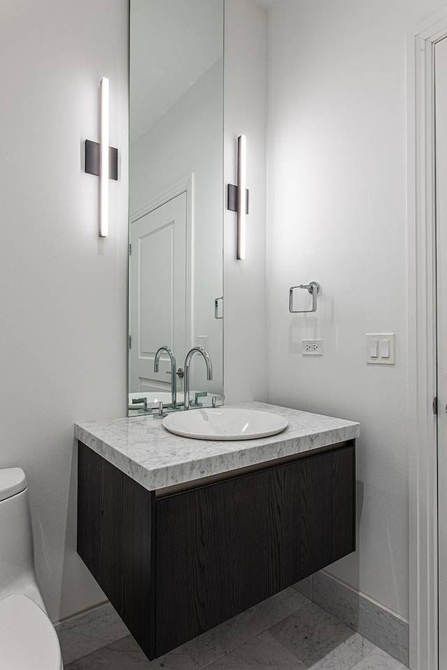 bathroom with baseboards, vanity, and toilet