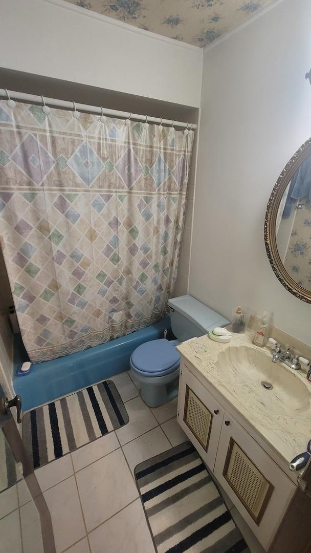 full bathroom with vanity, tile patterned floors, toilet, and shower / tub combo with curtain