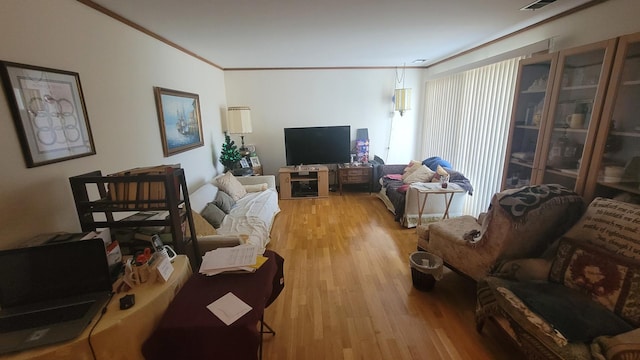 living room with light wood finished floors, visible vents, and crown molding