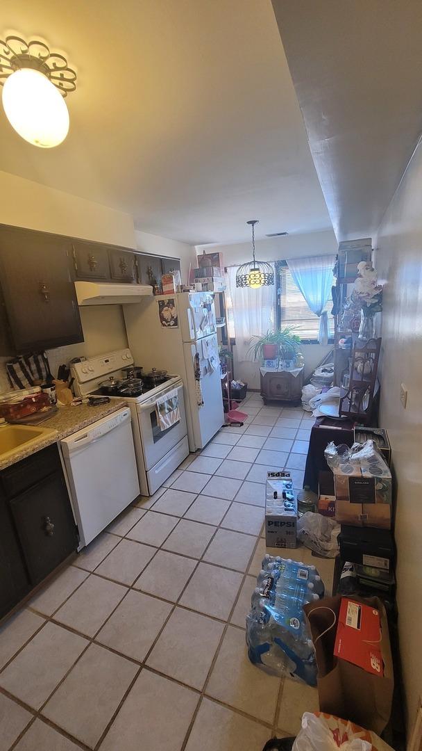 kitchen featuring white appliances, under cabinet range hood, light countertops, and light tile patterned flooring