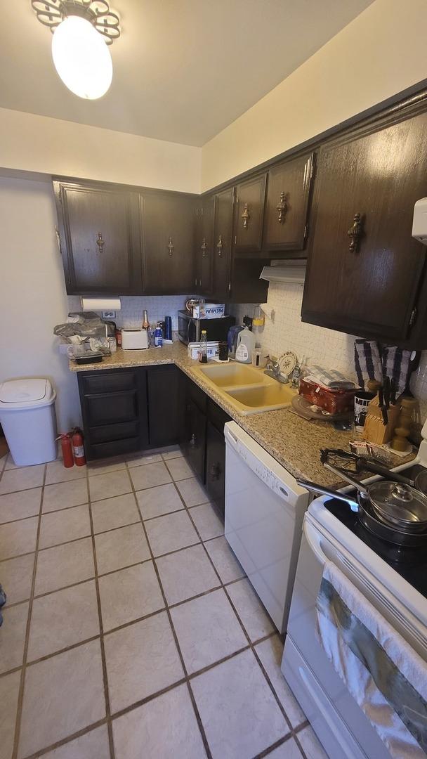 kitchen with white appliances, light tile patterned floors, decorative backsplash, light countertops, and a sink