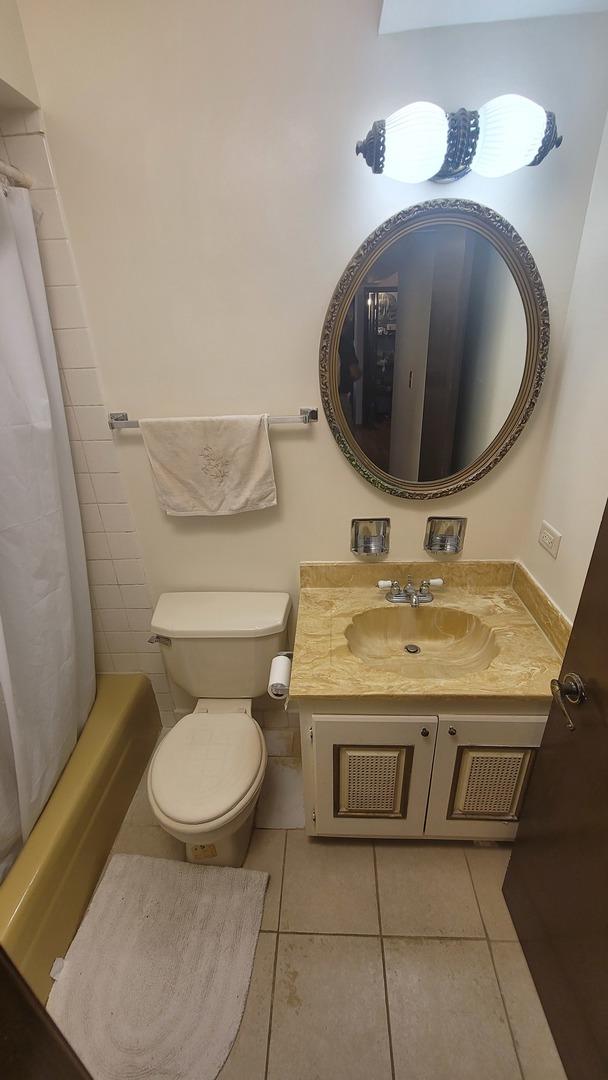 bathroom featuring toilet, shower / tub combo, vanity, and tile patterned floors