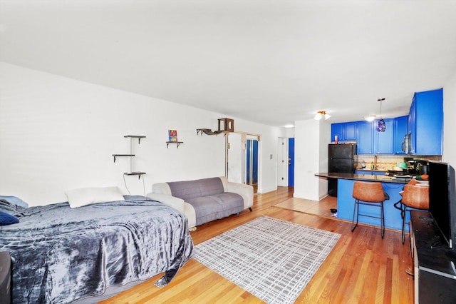 bedroom featuring light wood finished floors and freestanding refrigerator