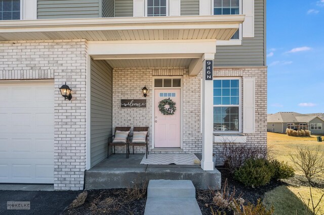 property entrance featuring a garage, covered porch, and brick siding