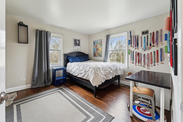 bedroom with multiple windows, wood finished floors, and baseboards