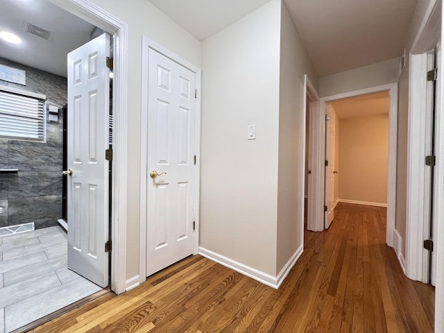 hall with visible vents, light wood-style flooring, and baseboards