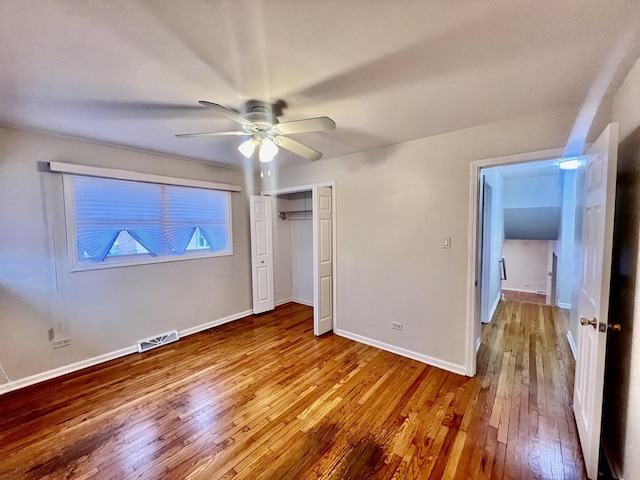 unfurnished bedroom featuring visible vents, baseboards, a ceiling fan, wood-type flooring, and a closet