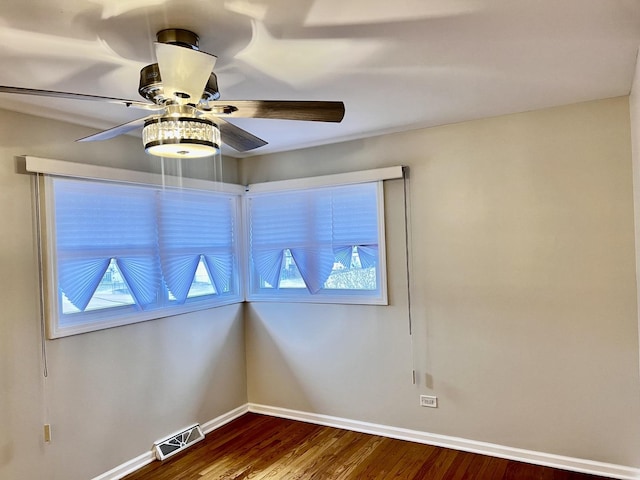 unfurnished room featuring dark wood-style floors, visible vents, baseboards, and a ceiling fan