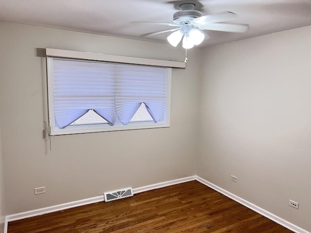 unfurnished room with visible vents, dark wood finished floors, baseboards, and ceiling fan