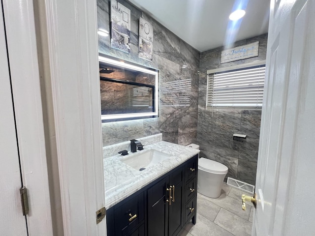 bathroom featuring toilet, visible vents, tile walls, and vanity