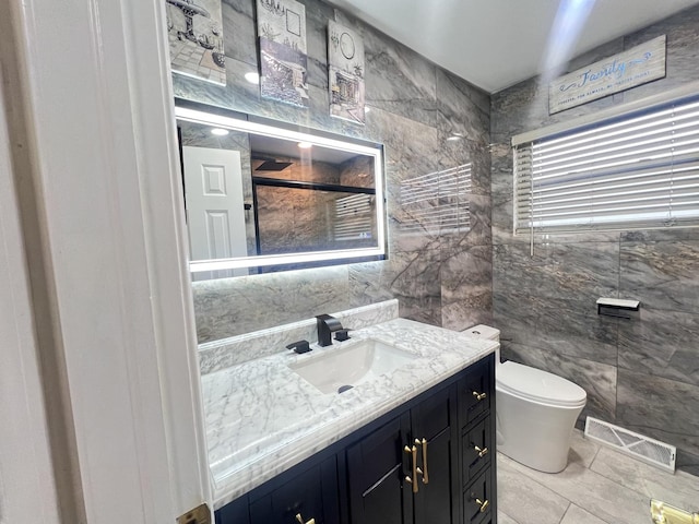 bathroom featuring visible vents, toilet, tile walls, and vanity