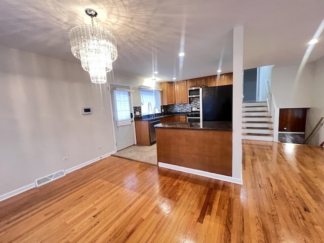 kitchen featuring visible vents, dark countertops, brown cabinets, refrigerator, and a sink