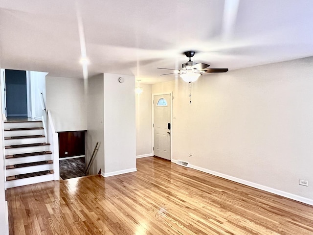 interior space with a ceiling fan, wood finished floors, visible vents, and baseboards