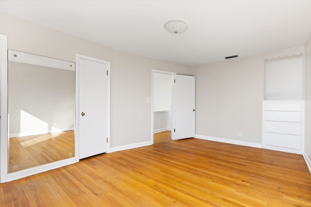 unfurnished bedroom featuring light wood finished floors, visible vents, and baseboards