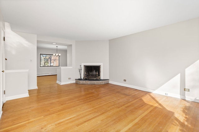 unfurnished living room with light wood-type flooring, a baseboard radiator, baseboards, and a fireplace with raised hearth