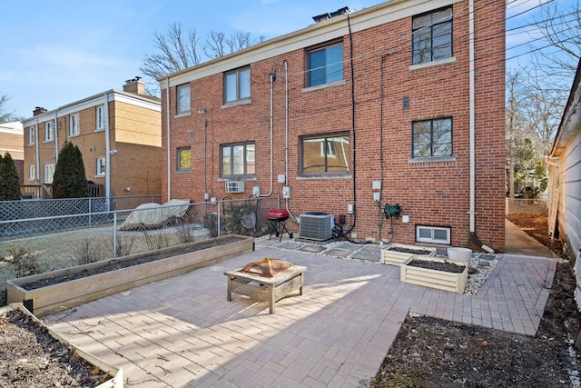 rear view of house with an outdoor fire pit, brick siding, and fence private yard