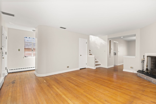 unfurnished living room featuring a fireplace, a baseboard radiator, visible vents, light wood-style floors, and stairs