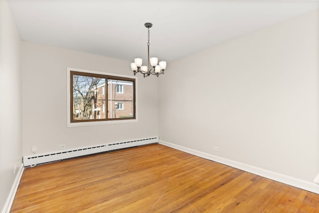 spare room with light wood-style floors, a baseboard radiator, baseboards, and a notable chandelier