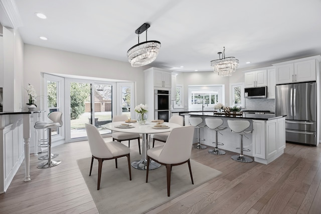 dining area with light wood-style flooring, recessed lighting, a wealth of natural light, and an inviting chandelier