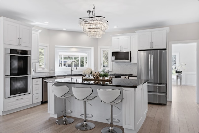 kitchen featuring appliances with stainless steel finishes, white cabinets, a sink, and a kitchen island