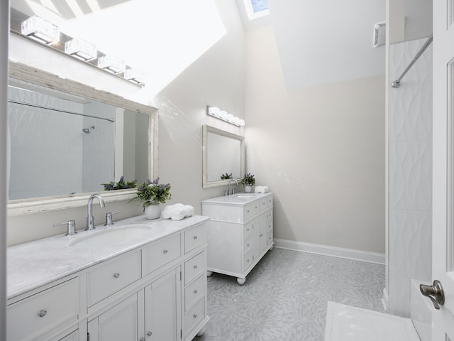 full bath with a skylight, two vanities, a sink, and baseboards