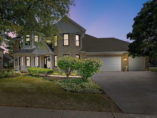 view of front of house featuring a garage, driveway, a shingled roof, a front yard, and brick siding