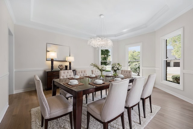 dining room with a chandelier, crown molding, light wood-type flooring, and baseboards