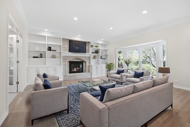 living room featuring crown molding, recessed lighting, a stone fireplace, wood finished floors, and baseboards