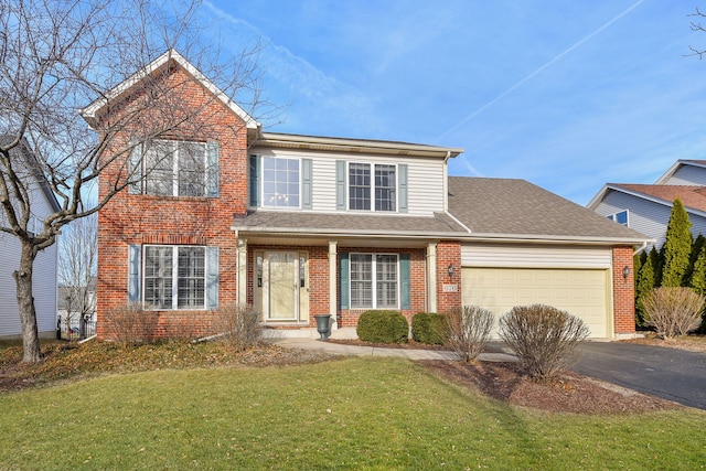 traditional-style house with aphalt driveway, roof with shingles, a front yard, a garage, and brick siding