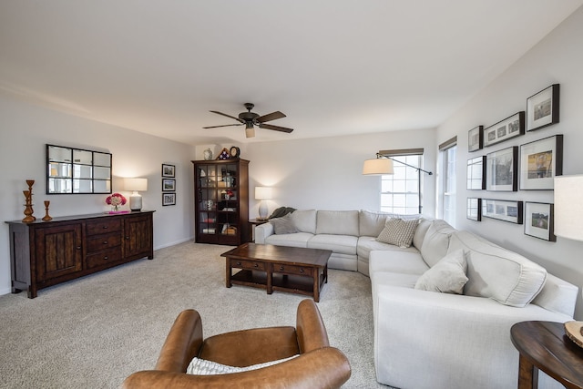 living room with light carpet, baseboards, and ceiling fan