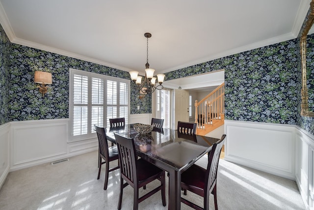 dining area with wallpapered walls, ornamental molding, visible vents, and wainscoting