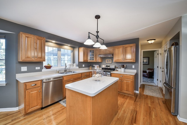 kitchen with under cabinet range hood, stainless steel appliances, light countertops, and a sink