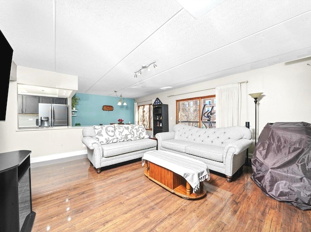 living area featuring a textured ceiling, baseboards, and wood finished floors