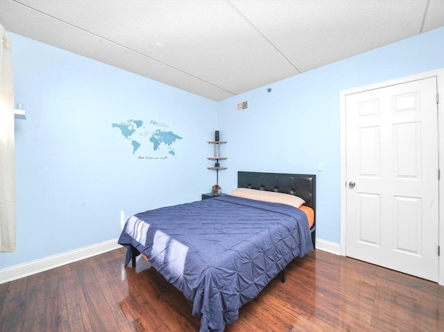 bedroom featuring visible vents, baseboards, a textured ceiling, and wood finished floors