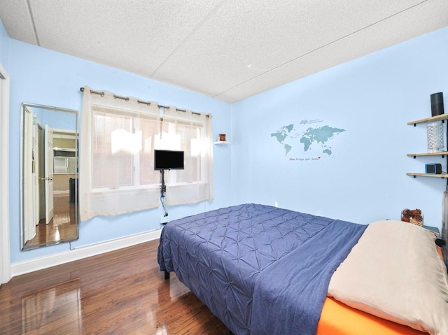 bedroom with a textured ceiling, baseboards, and wood finished floors