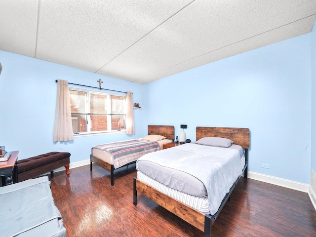 bedroom featuring a textured ceiling, baseboards, and wood finished floors