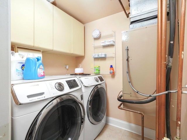 washroom featuring light tile patterned floors, cabinet space, baseboards, and washing machine and clothes dryer