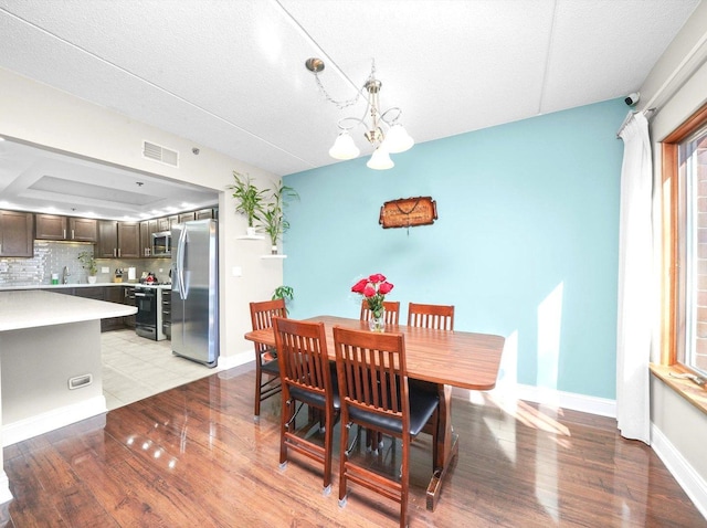 dining room featuring light wood-style flooring, baseboards, visible vents, and a chandelier