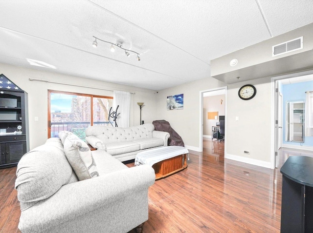 living area featuring visible vents, baseboards, a textured ceiling, and wood finished floors