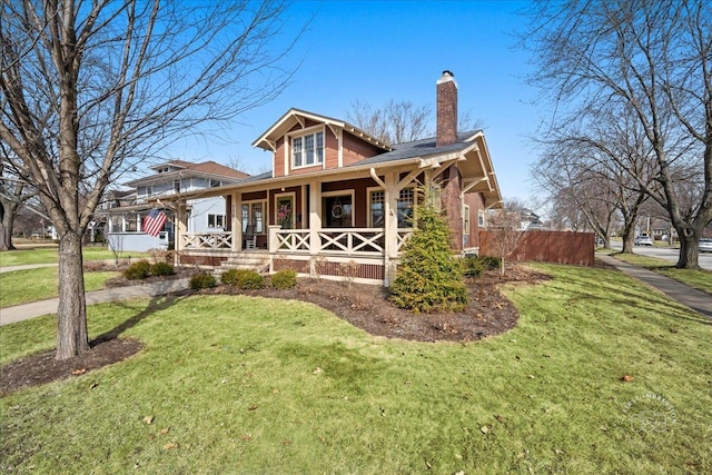 bungalow with a porch, a chimney, and a front lawn