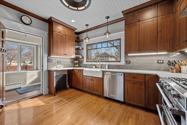 kitchen with a sink, a baseboard radiator, appliances with stainless steel finishes, and light countertops