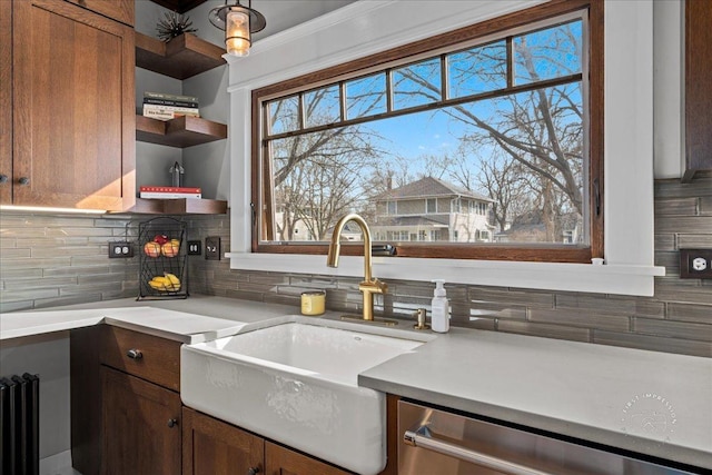 kitchen with a sink, open shelves, stainless steel dishwasher, light countertops, and decorative backsplash