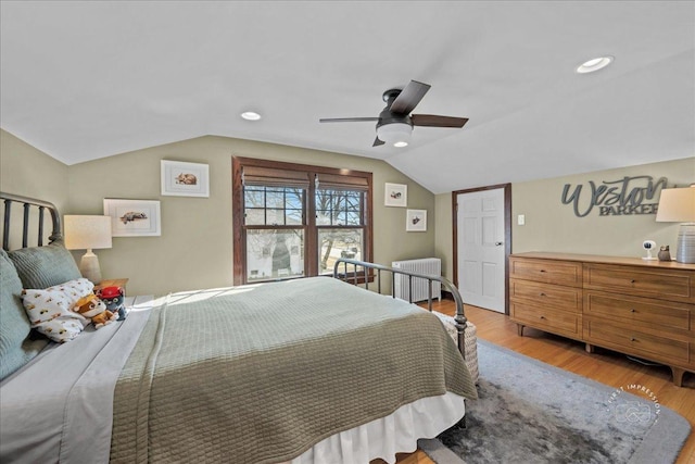 bedroom with a ceiling fan, vaulted ceiling, radiator heating unit, and wood finished floors