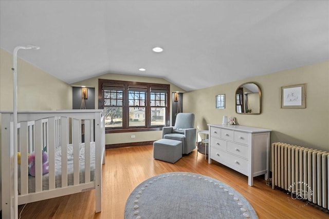 bedroom featuring radiator heating unit, recessed lighting, light wood-style floors, baseboards, and vaulted ceiling