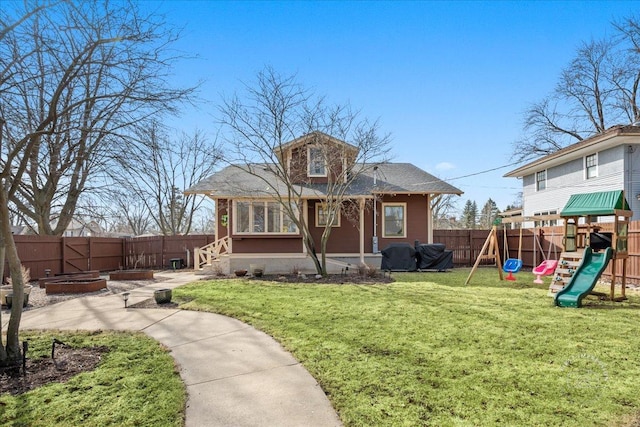 rear view of house featuring a yard, a playground, and a fenced backyard