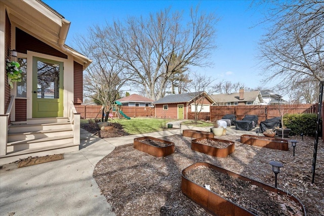 view of yard with an outbuilding, entry steps, a playground, and a fenced backyard