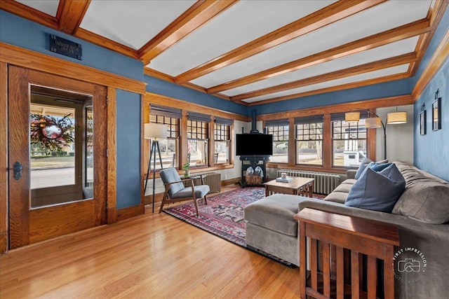 living area featuring baseboards, beam ceiling, wood finished floors, and radiator heating unit