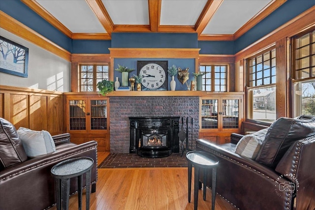 living area featuring beam ceiling, a wood stove, and wood finished floors