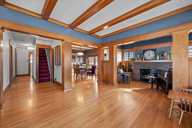 living room featuring beamed ceiling, baseboards, hardwood / wood-style floors, and stairway